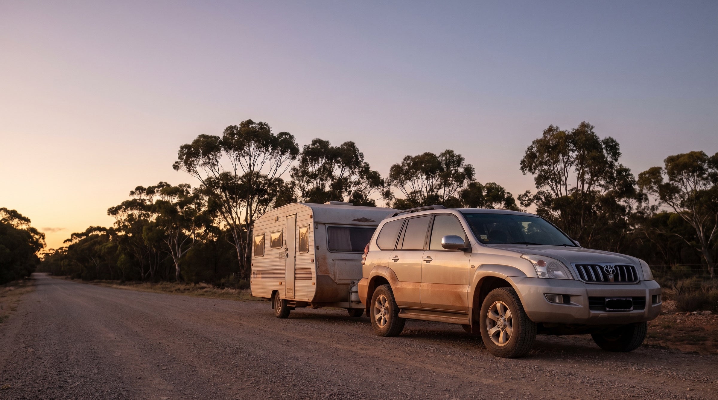 Toyota Prado towing a caravan at dusk on an Australian coastal road