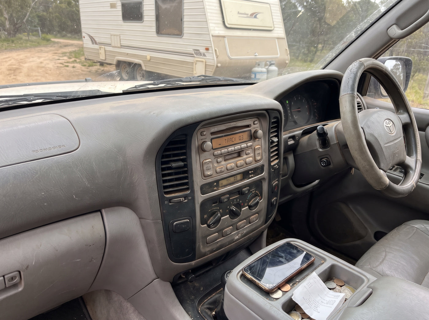Dashboard of an older LandCruiser with a factory CD stereo, caravan ahead